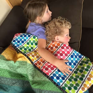 snuggling kiddos under rainbow quilt